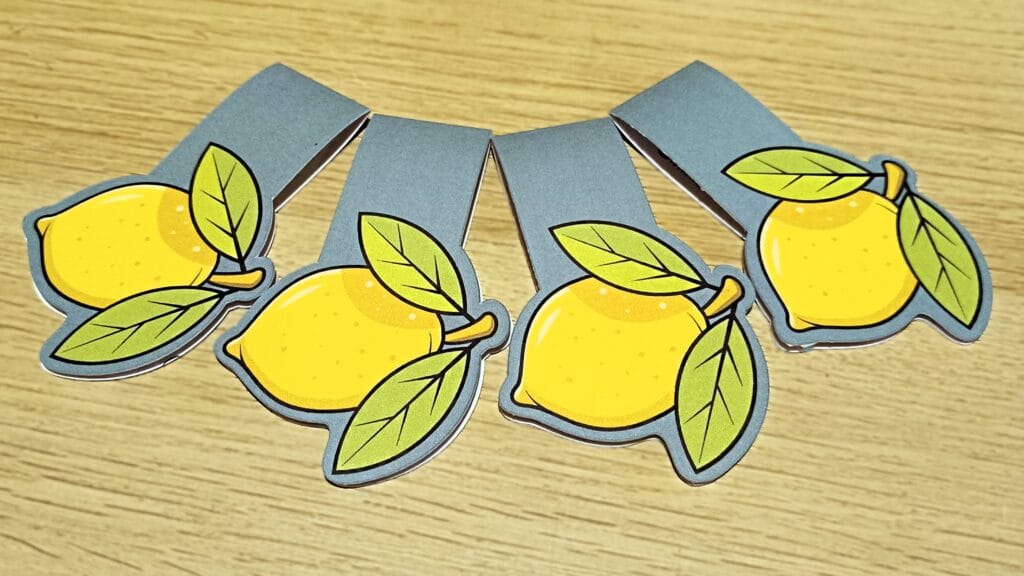 Quatre marque-page de modèle citron doux de la collection fruits de poramor.ch sur une table en bois claire.